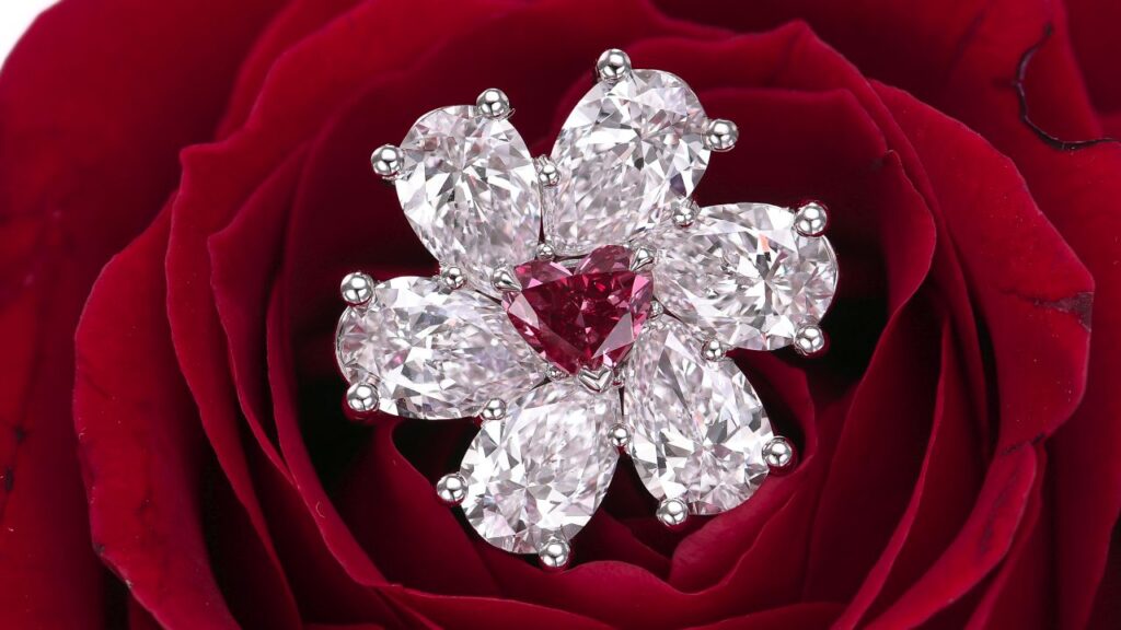 A Leibish custom made flower ring set with a heart-shaped, 0.29-carat, fancy-purplish-red Argyle diamond surrounded by pear-cut, D-color white diamonds